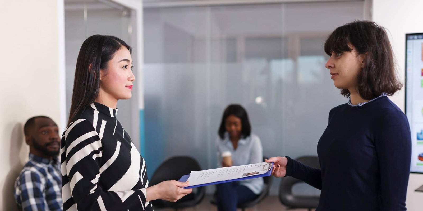 Two professionals reviewing hiring documents in a modern office