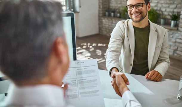 Job interview handshake with a resume on the desk