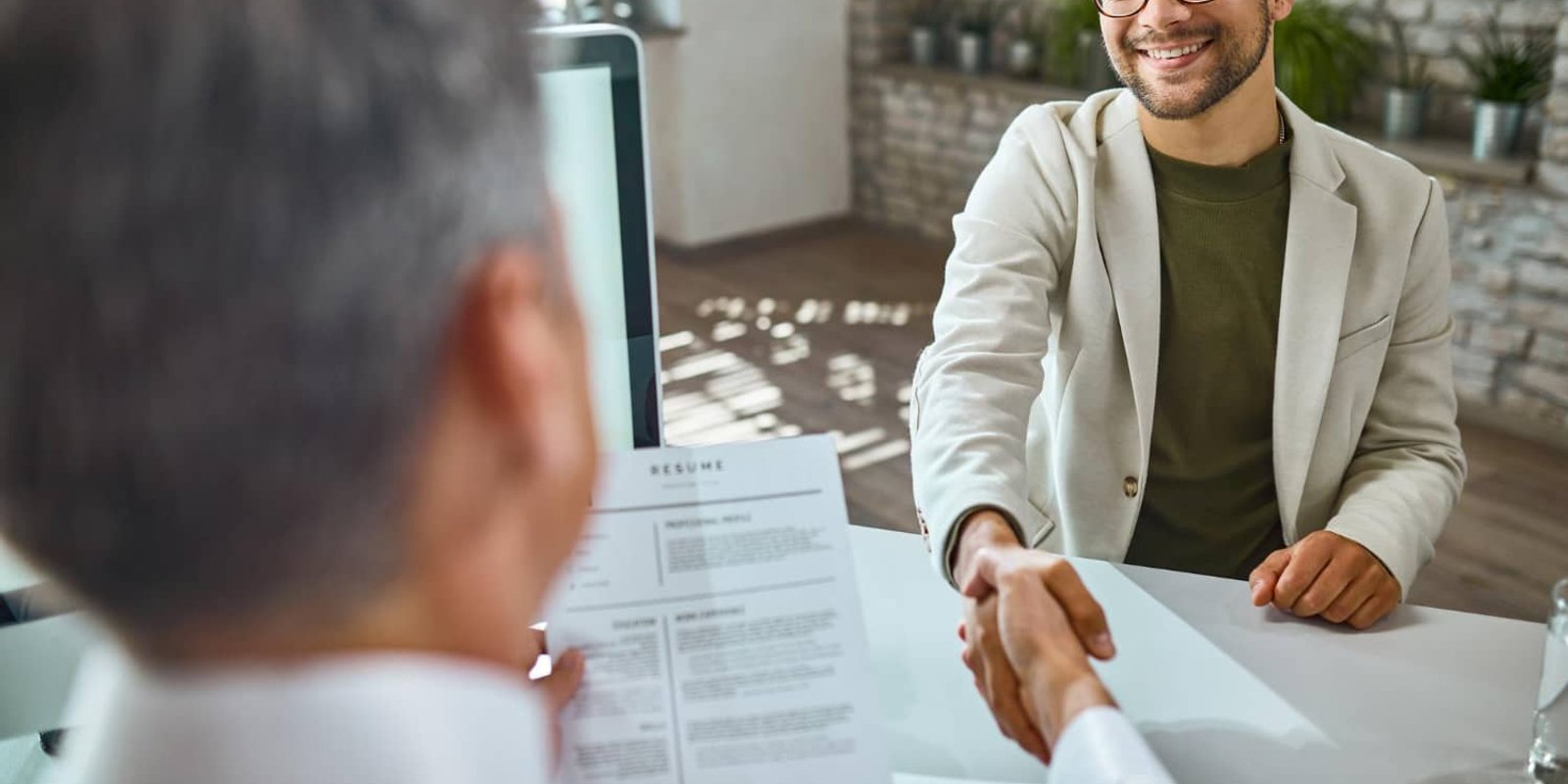Job interview handshake with a resume on the desk