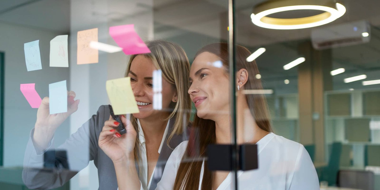 Two professionals mapping employer brand ideas on a glass wall
